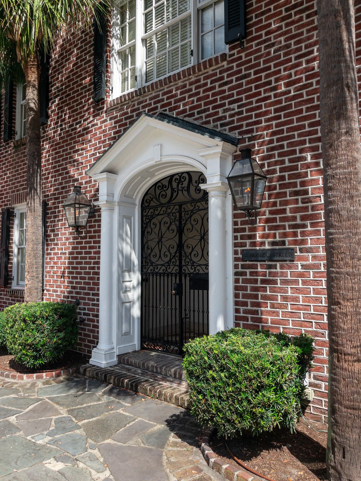 Brick home entrance with an arched wrought iron gate